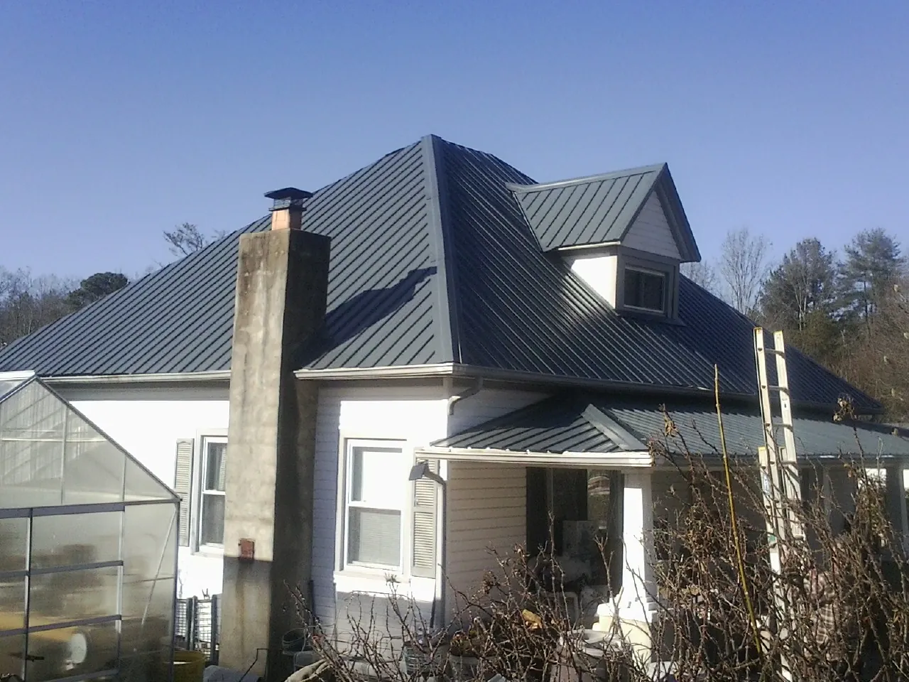 Dark blue standing seam metal roof on a white farmhouse with dormer — Slate & Tile Roof Repair by Roofing Brothers in Ingomar