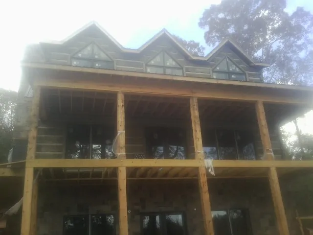 Dormers and porch framing on a large log home under construction — Roof Coating work by our crew in Ingomar