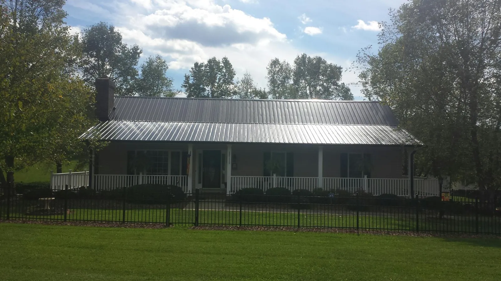 Gray metal roof on a brick ranch with a full width front porch — Gutter Guard Installation work by our crew in Ingomar
